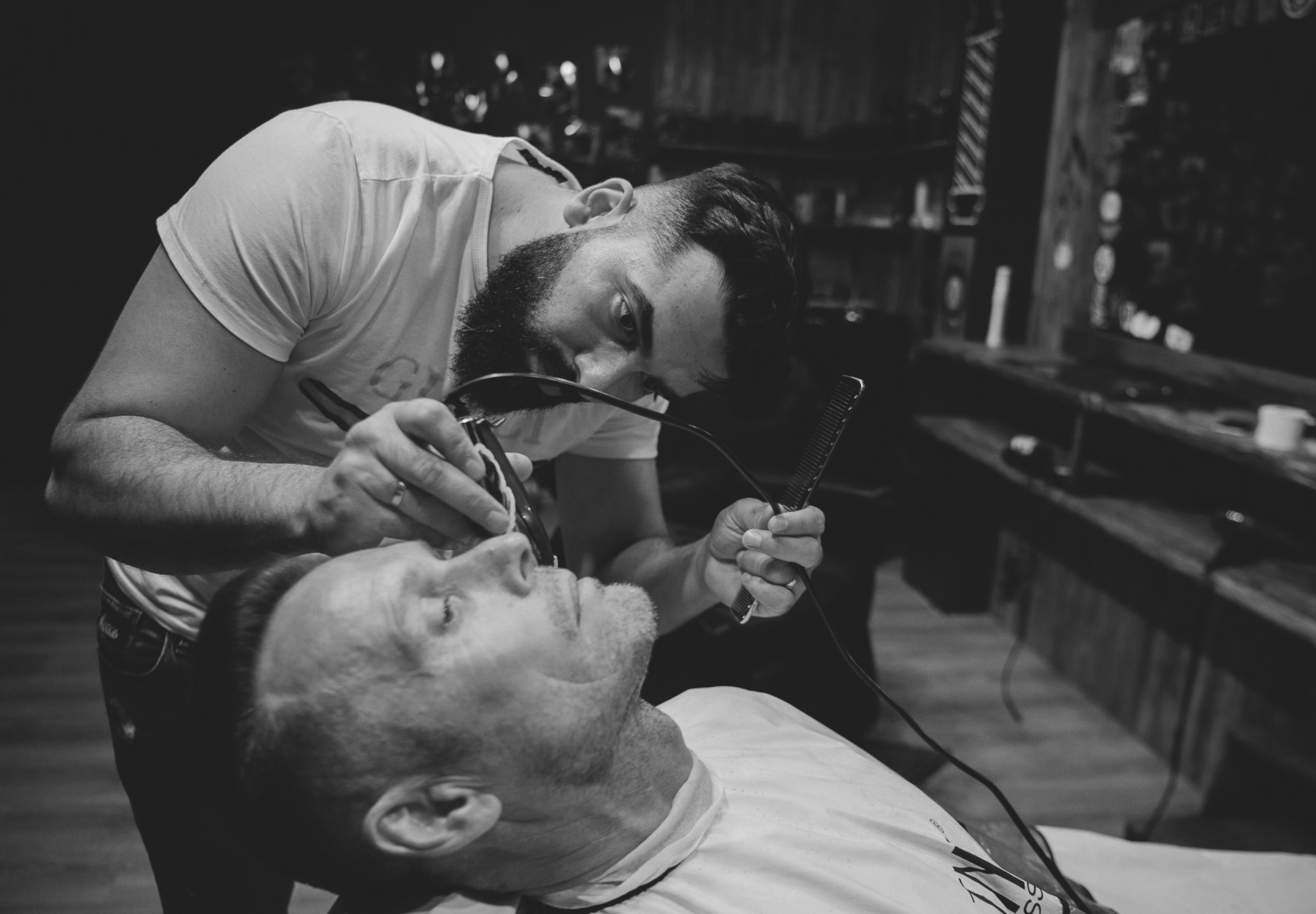 Барбер бреет клиента электрической бритвой