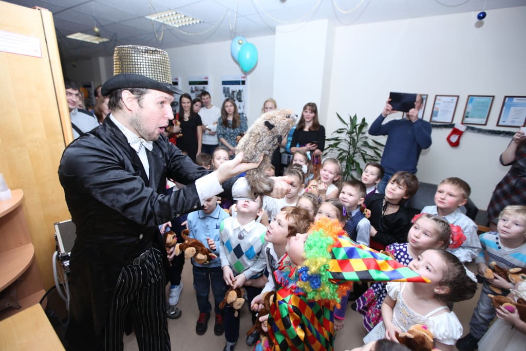 Фокусник в шляпе показывает фокусы детям